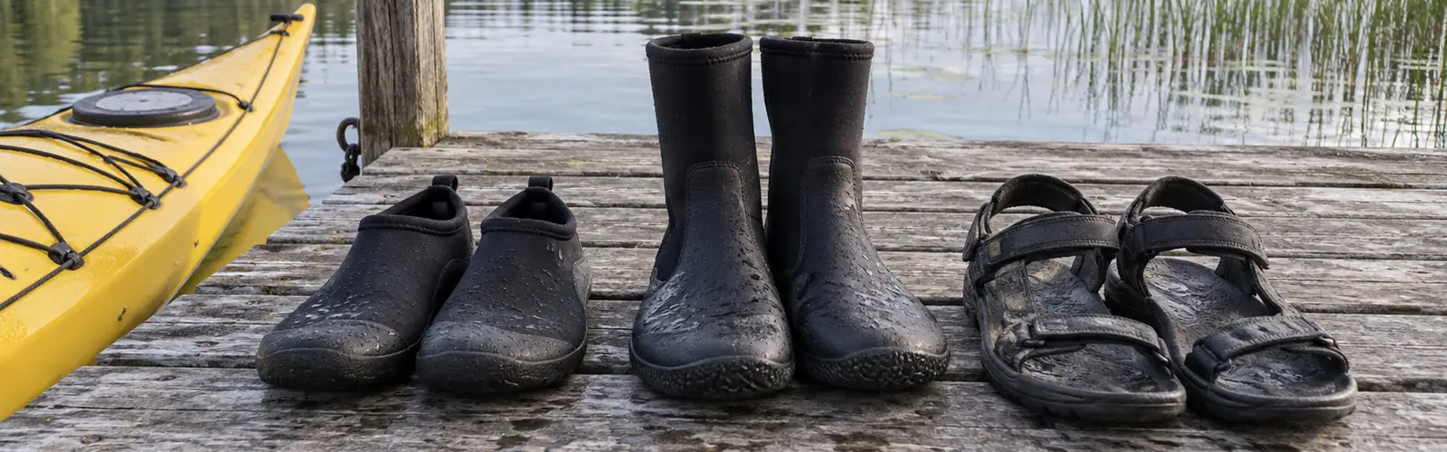 Neoprenskor, paddelstövlar och sandaler uppställda på en brygga bredvid en gul kajak