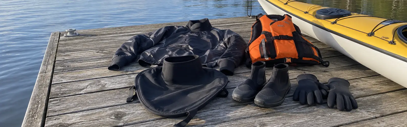 Paddelkläder utlagda på en brygga bredvid en gul havskajak