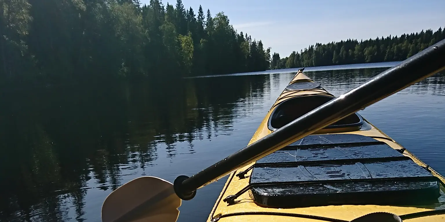 Kajakens för mot en stilla skogssjö